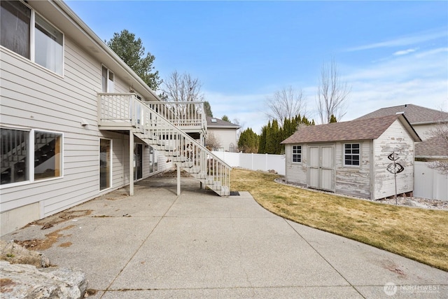 view of patio / terrace featuring stairway, fence, an outdoor structure, a storage unit, and a deck