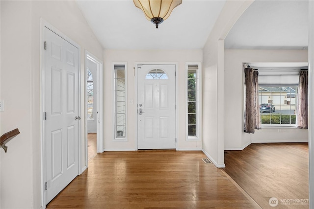 entryway with visible vents, wood finished floors, baseboards, and arched walkways