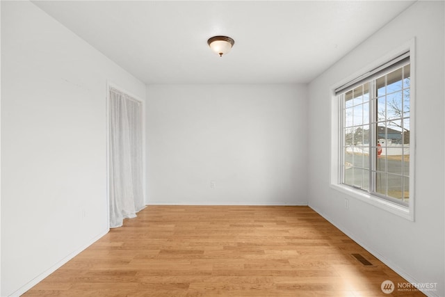 empty room with visible vents, baseboards, and light wood-style floors