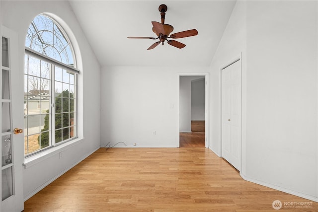 unfurnished room with plenty of natural light, a ceiling fan, light wood-style floors, and high vaulted ceiling