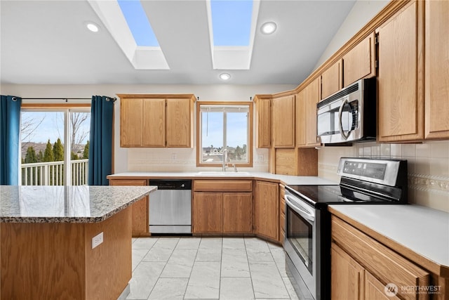 kitchen featuring marble finish floor, a sink, recessed lighting, appliances with stainless steel finishes, and a skylight