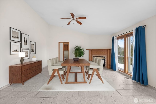 dining area featuring a glass covered fireplace, lofted ceiling, a ceiling fan, and visible vents