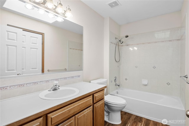 bathroom with visible vents, toilet, bathing tub / shower combination, wood finished floors, and vanity