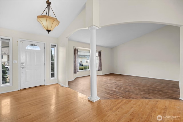 entryway featuring arched walkways, high vaulted ceiling, ornate columns, and wood finished floors