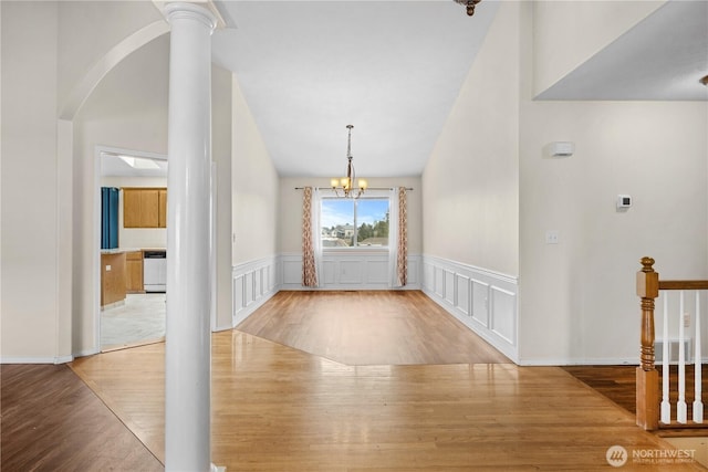 entryway with a decorative wall, wood finished floors, arched walkways, and a chandelier