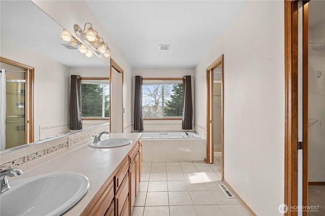 bathroom with tile patterned floors, visible vents, a bath, and a sink