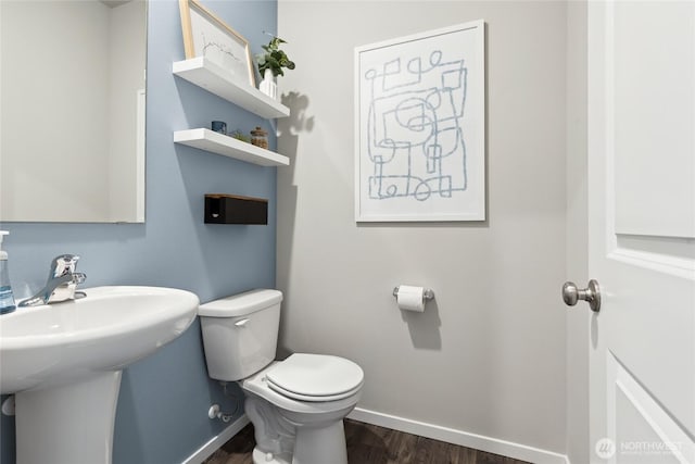 bathroom featuring a sink, baseboards, toilet, and wood finished floors