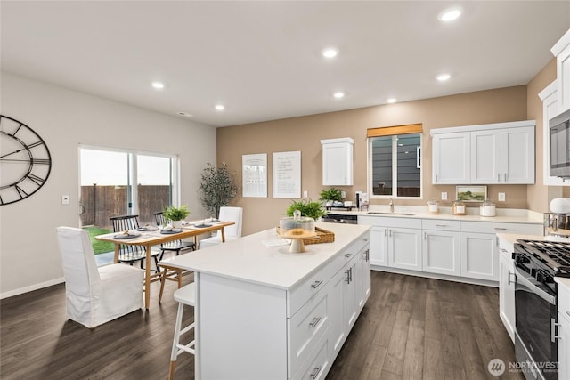 kitchen with recessed lighting, dark wood-type flooring, white cabinets, appliances with stainless steel finishes, and a center island