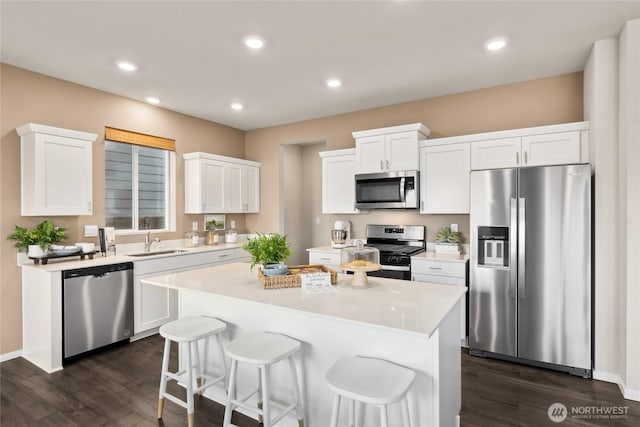 kitchen featuring a center island, white cabinetry, stainless steel appliances, and a sink