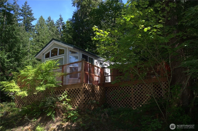 rear view of property with a wooded view and a wooden deck