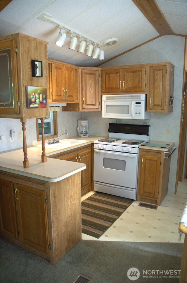 kitchen featuring white appliances, lofted ceiling, a sink, light countertops, and dark floors