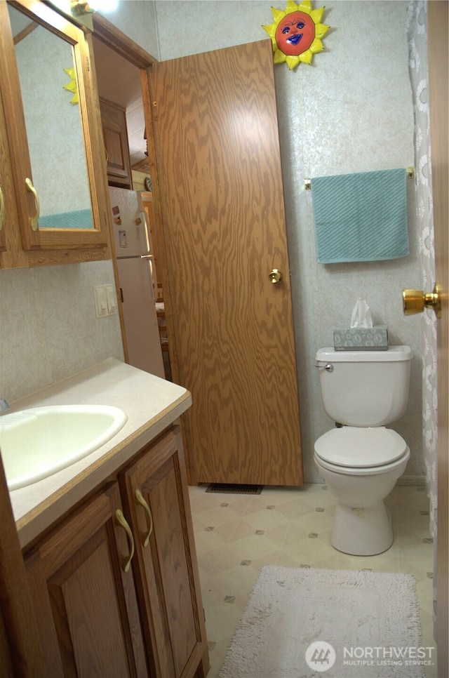 half bathroom featuring tile patterned floors, toilet, and vanity