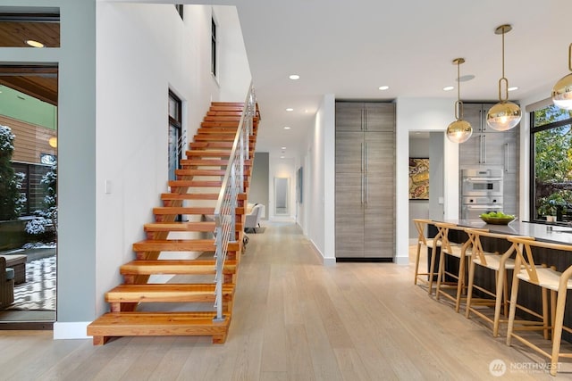 interior space featuring recessed lighting, light wood-type flooring, baseboards, and stairs