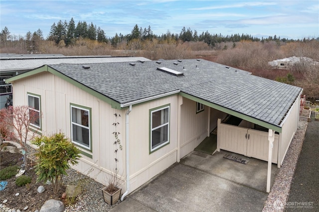 view of property exterior featuring a carport and a shingled roof