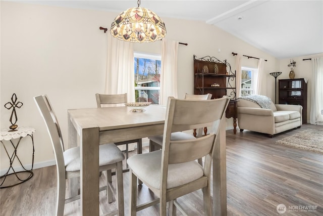 dining room with a wealth of natural light, vaulted ceiling with beams, baseboards, and wood finished floors