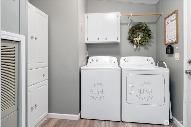 washroom with cabinet space, baseboards, light wood finished floors, and washing machine and clothes dryer