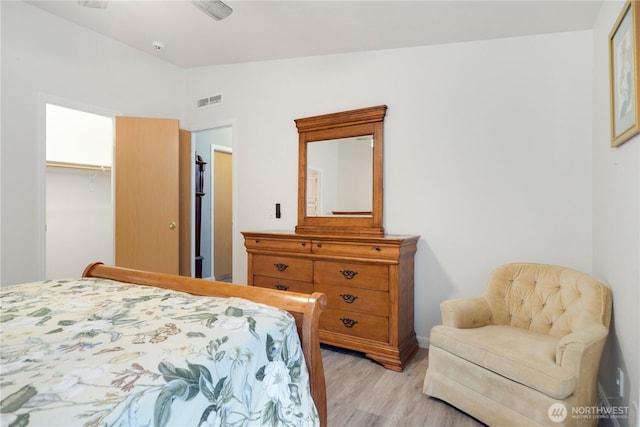 bedroom with a closet, visible vents, light wood-style flooring, and lofted ceiling