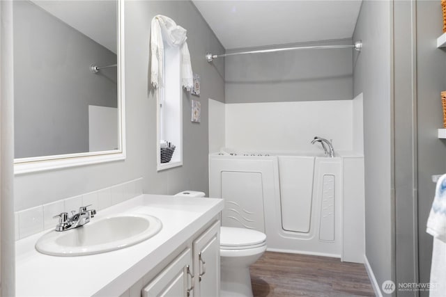 full bathroom with vanity, wood finished floors, toilet, and a bathtub