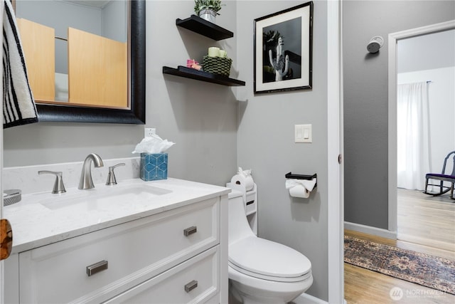 bathroom featuring vanity, toilet, wood finished floors, and baseboards