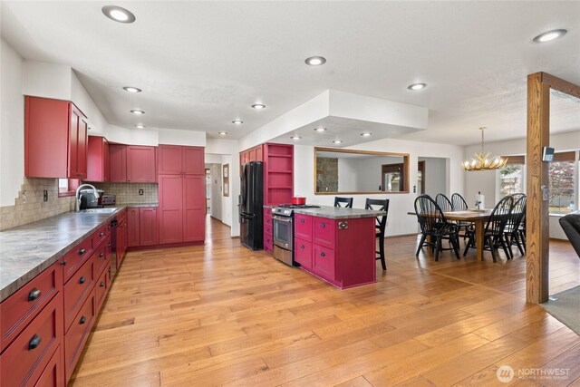 kitchen featuring a notable chandelier, light wood-style flooring, open shelves, a sink, and appliances with stainless steel finishes