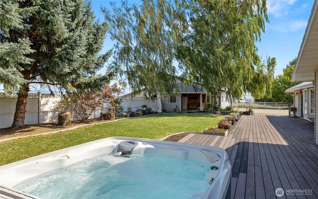 exterior space featuring fence, a lawn, and hot tub deck surround