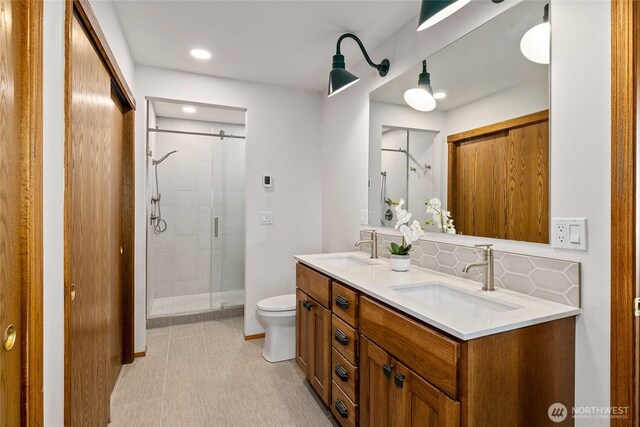 full bathroom with decorative backsplash, a shower stall, and a sink