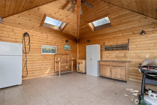 misc room with ceiling fan, wooden walls, a skylight, and high vaulted ceiling