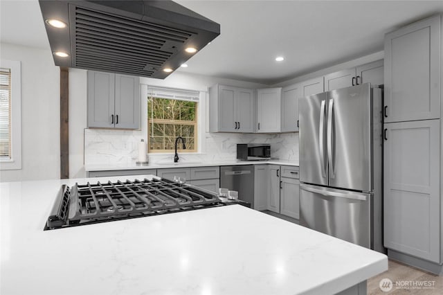 kitchen with extractor fan, light countertops, appliances with stainless steel finishes, and a sink