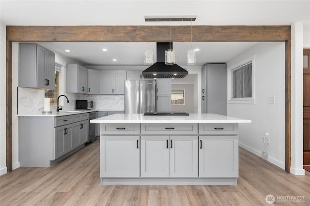 kitchen featuring gray cabinets, a kitchen island, stainless steel appliances, exhaust hood, and light countertops