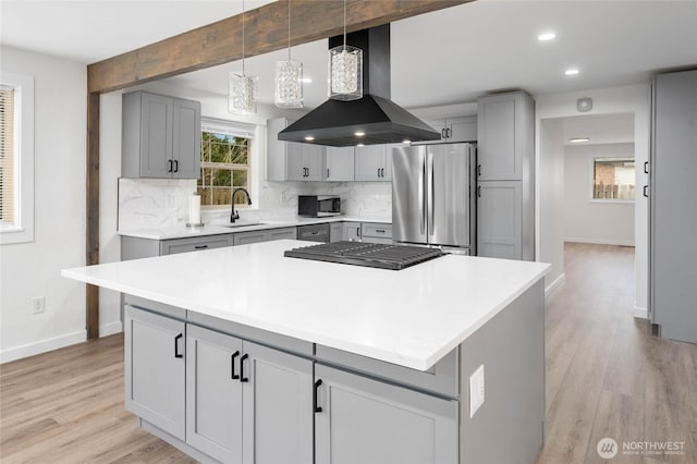 kitchen with backsplash, beam ceiling, gray cabinets, exhaust hood, and stainless steel appliances