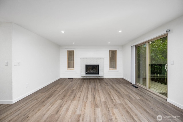 unfurnished living room with a fireplace, recessed lighting, wood finished floors, and baseboards