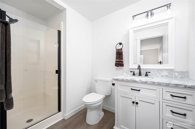 full bathroom featuring a shower stall, baseboards, toilet, wood finished floors, and vanity