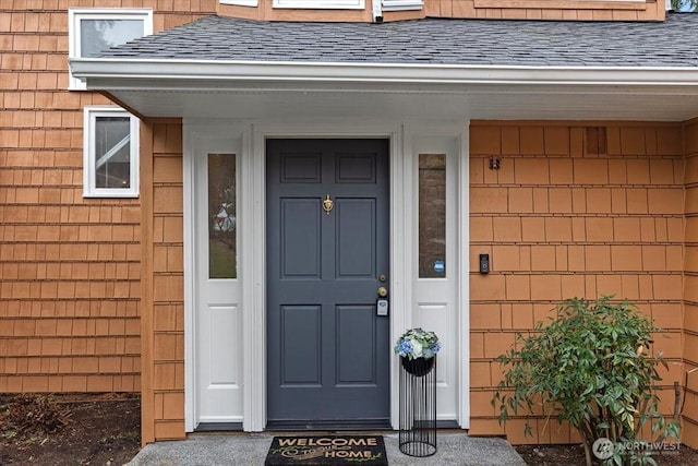 view of exterior entry with a shingled roof