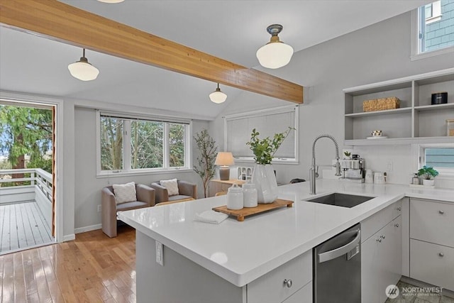 kitchen featuring a peninsula, a sink, light countertops, light wood-style floors, and dishwasher