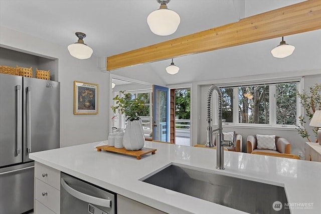 kitchen with pendant lighting, a sink, appliances with stainless steel finishes, light countertops, and vaulted ceiling with beams