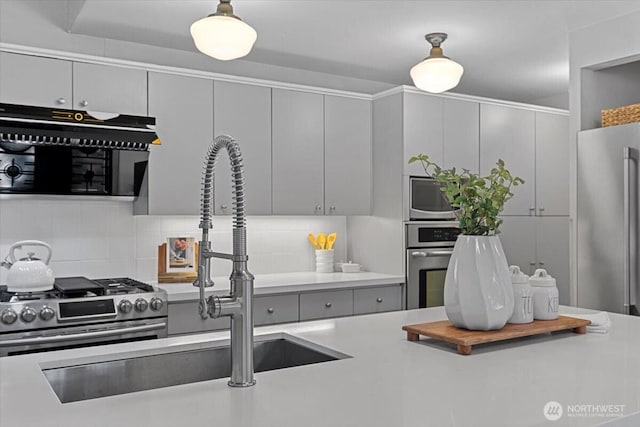 kitchen featuring gray cabinets, a sink, light countertops, appliances with stainless steel finishes, and tasteful backsplash