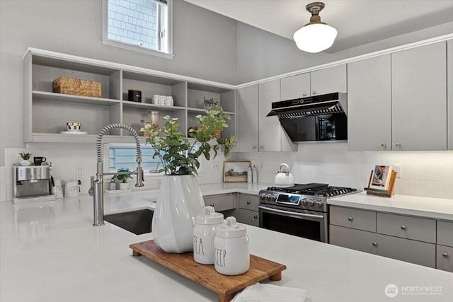 kitchen with gray cabinets, a sink, open shelves, decorative backsplash, and gas range