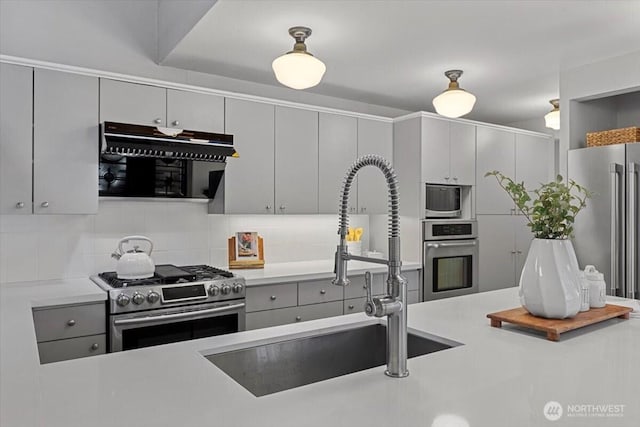 kitchen featuring decorative backsplash, gray cabinets, stainless steel appliances, and a sink