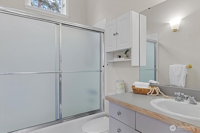 bathroom featuring vanity, toilet, and bath / shower combo with glass door