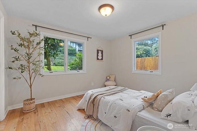 bedroom featuring baseboards, multiple windows, and light wood finished floors