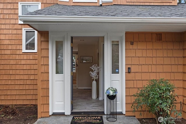 doorway to property with a shingled roof