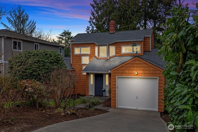 view of front of house with concrete driveway, a chimney, a garage, and a shingled roof