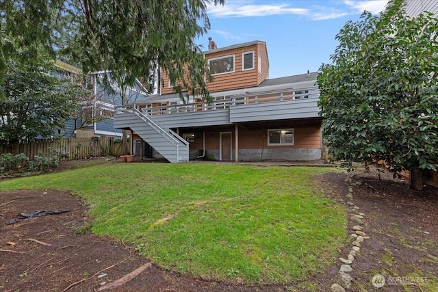 rear view of house with stairway, a lawn, a deck, and fence