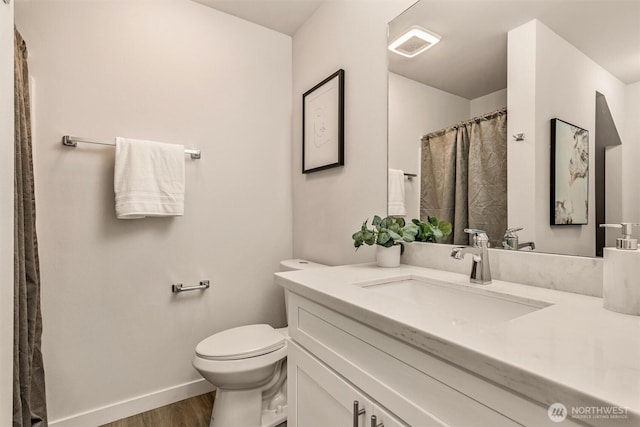 bathroom featuring visible vents, baseboards, toilet, wood finished floors, and vanity