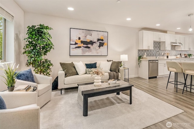 living area featuring recessed lighting, baseboards, and light wood-style flooring