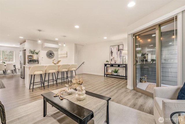 living room featuring recessed lighting, light wood-type flooring, baseboards, and an AC wall unit