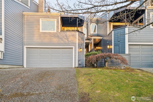 view of front of property with gravel driveway, a front lawn, a garage, and a chimney