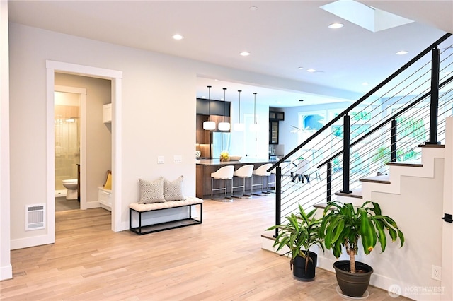 stairway featuring recessed lighting, baseboards, wood finished floors, and a skylight