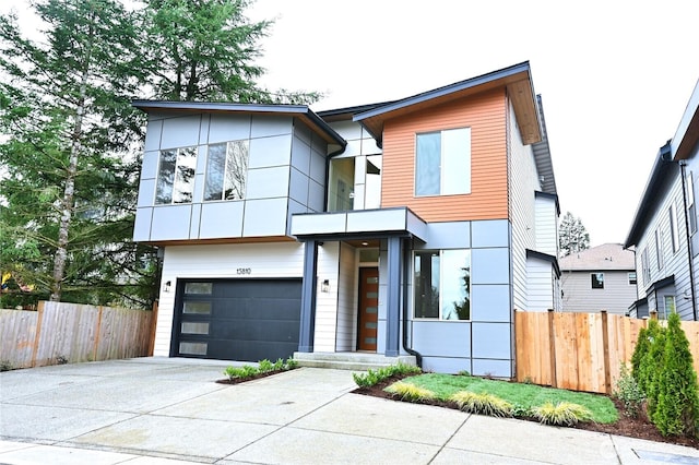 modern home with concrete driveway, a garage, and fence