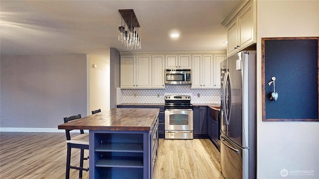 kitchen featuring light wood finished floors, open shelves, decorative backsplash, appliances with stainless steel finishes, and butcher block counters